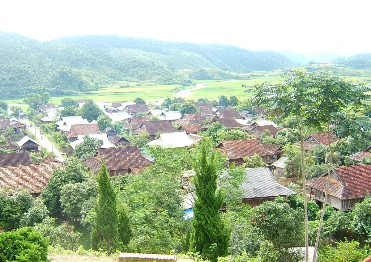 Nhìn từ trên đồi xuống một xóm nhà sàn mái ngói đỏ nằm giữa những cánh đồng xanh ở Mộc Châu.
